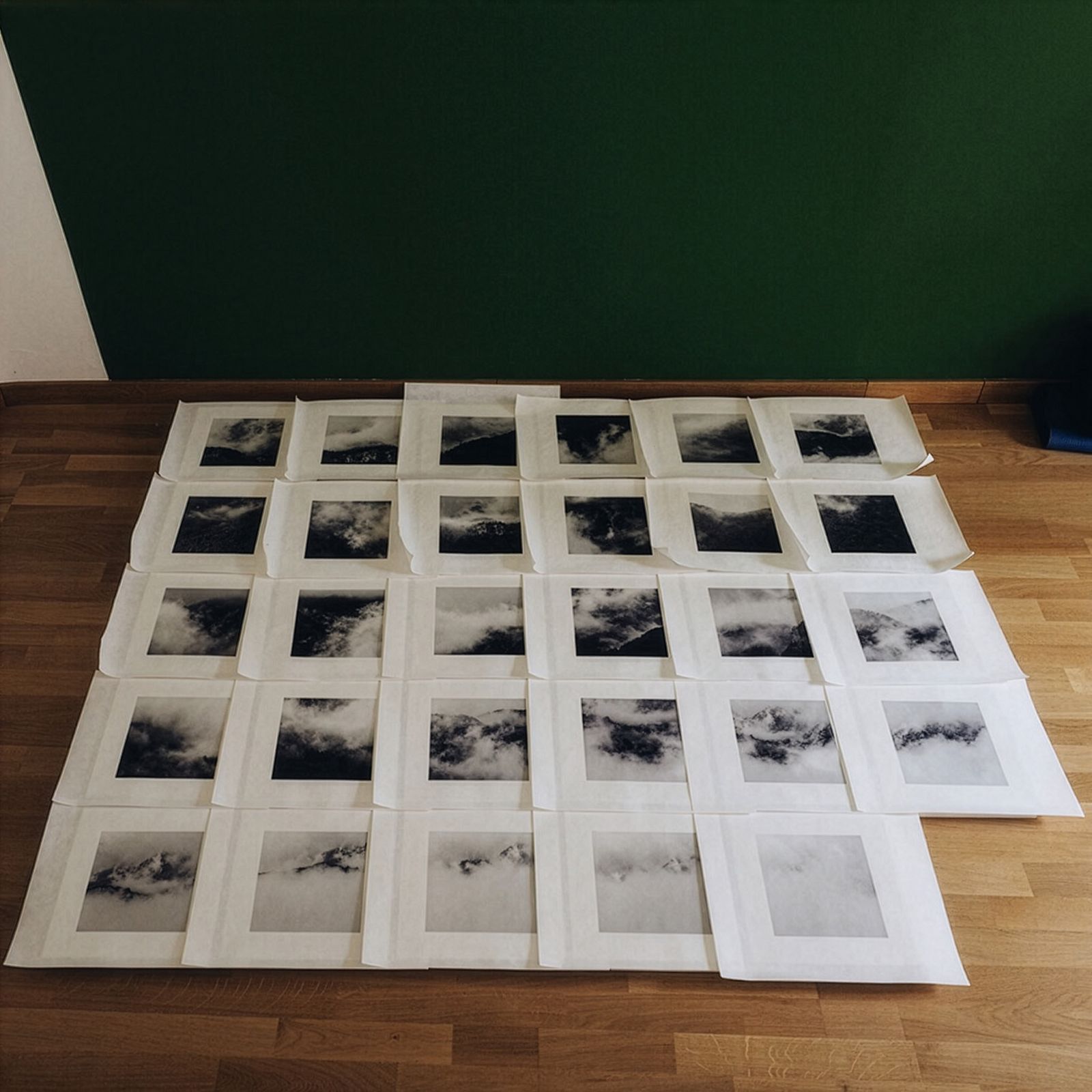 Una cuadrícula de fotografías en blanco y negro dispuestas en un suelo de madera.